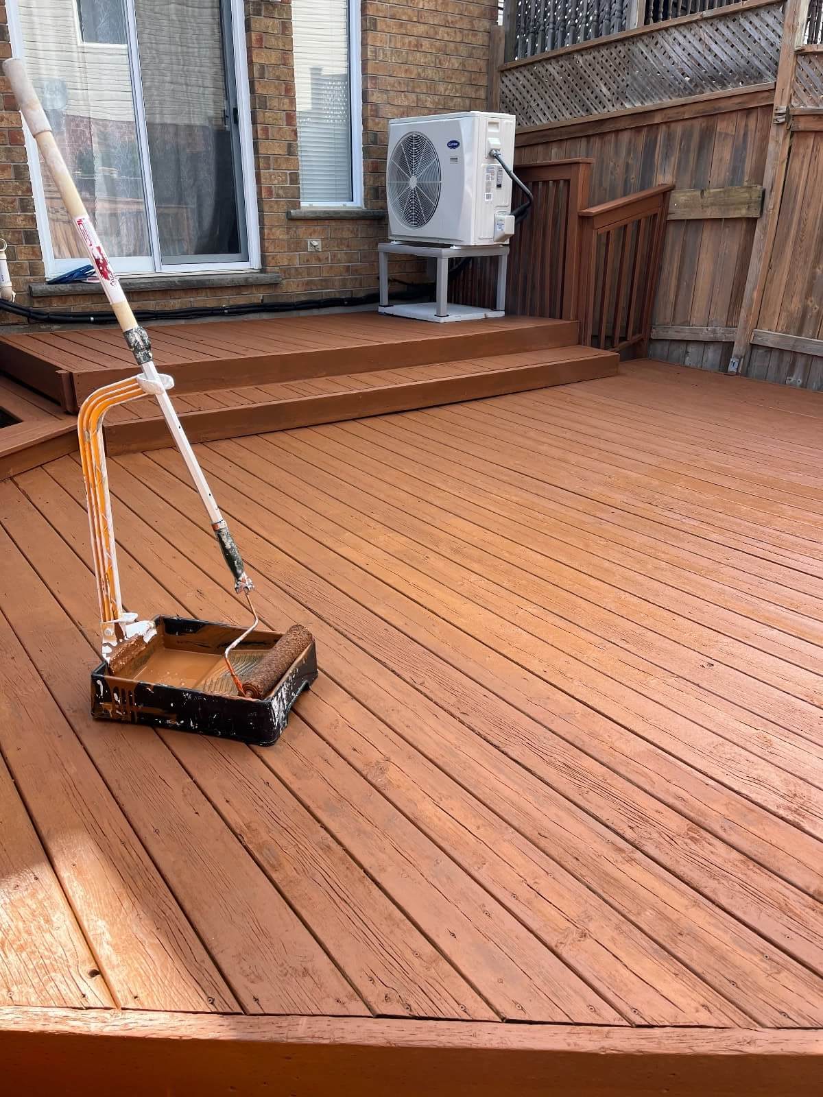 Freshly stained deck with a paint brush roller, and tray in view, illustrating Fit Painting's thorough deck staining & painting services in Kitchener-Waterloo.